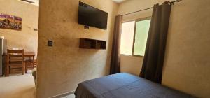 a bedroom with a bed and a television on the wall at Departamentos MG in Valladolid