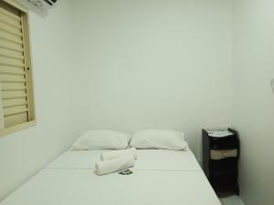 uma cama branca num quarto com uma janela em Pousada automática sem recepção 2 em Uberlândia