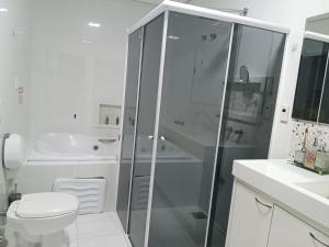 uma casa de banho branca com um chuveiro e um WC. em Pousada automática sem recepção 2 em Uberlândia