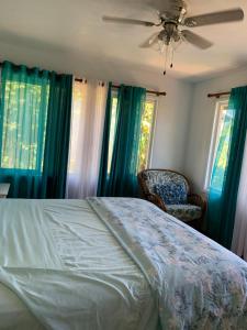 a bedroom with a bed and a chair and windows at The Hale at Ohi'a Kai, upstairs unit, TVNCU#1355 in Waipouli