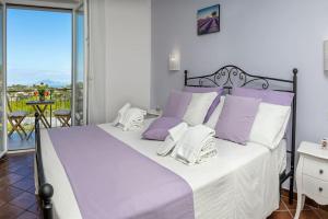 1 dormitorio con 1 cama grande con almohadas moradas y blancas en Casa La Cycas, en Massa Lubrense