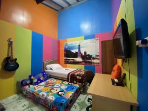 a colorful room with a bed and a guitar in it at Pelemkecut Double-Degree Syariah Accommodation in Kejayan