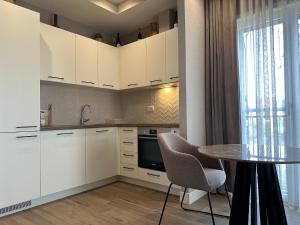 a kitchen with white cabinets and a table and a window at LUSTICA BAY GARDEN STUDIO, Centrale in Tivat