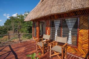 une cabine avec une terrasse dotée de chaises et d'un toit de chaume dans l'établissement Njobvu Safari, à Kakumbi
