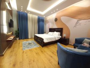 a bedroom with a bed and two blue chairs at Royal Lodge By Hotel Demanchi in Murree