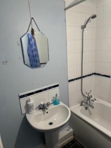 een badkamer met een wastafel, een spiegel en een bad bij Thames River Side Townhouse in Thamesmead