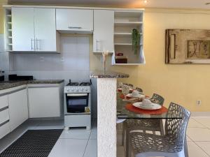 a kitchen with white cabinets and a table and chairs at (304) Sea and Sun at Litorânea Beach in Pimenta