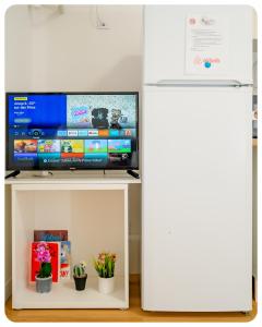 a television on a white stand next to a refrigerator at 2 pièces entre Paris et Disney in Villiers-sur-Marne