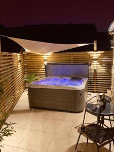 a large hot tub in a patio with a table at Tranquil retreat with hot tub in Stoke Bruerne