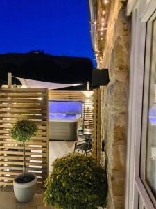 a patio with a bed and a potted plant at Tranquil retreat with hot tub in Stoke Bruerne +8 photos