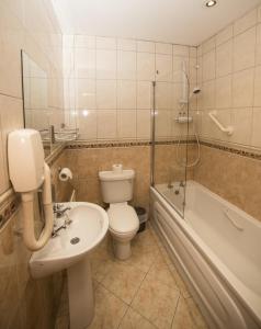 a bathroom with a sink and a toilet and a bath tub at The Frontier Hotel in Bridgend