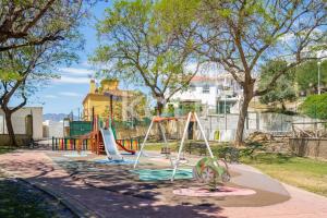 um parque infantil com três escorregas e um baloiço em Koti Rentals - Nenúfar em Fuengirola