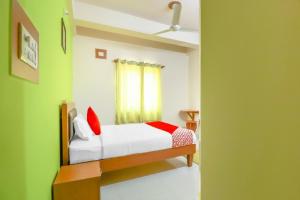 a bedroom with a bed with white sheets and red pillows at 79522 The Host in Bangalore