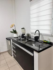 eine Küche mit einer schwarzen Arbeitsplatte und einem Waschbecken in der Unterkunft Acogedor independiente-Casa JH A in Santa Cruz de la Sierra