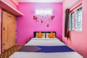 a bedroom with a pink wall and a bed at SPOT ON M R Plaza in Bhubaneshwar
