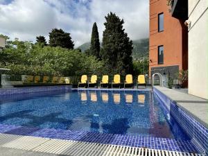 a swimming pool with yellow chairs next to a building at Hotel Del Medio in Sutomore