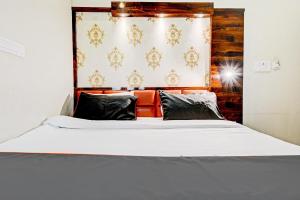 a bed with white sheets and black pillows at Hotel Tejesvi in Jaipur
