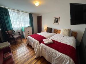 1 dormitorio con 2 camas y 1 silla en St. Gallen Haus, en Quito