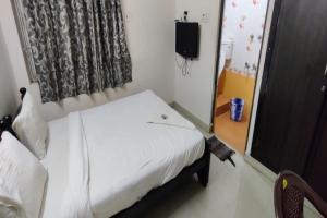 a small bedroom with a white bed and a television at SPOT ON The Grand Guest House Near PVR Cinemas Skywalk in Chennai