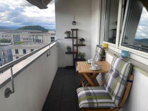 d'un balcon avec deux chaises, une table et une fenêtre. dans l'établissement TAMLiving Zentrum Luxus Parken Messe WIFI Traumaussicht Sunrise&Sunset, à Graz