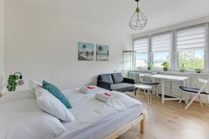 a white living room with a couch and a kitchen at Wave Apartments - Aurora in Gdynia