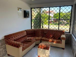 Sofá marrón en una habitación con ventana en Mirador El paraiso glamping, en Villavicencio