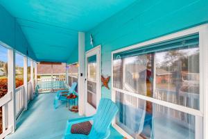 a blue house with two chairs on a porch at Blue Heaven Beach House in Rockaway Beach