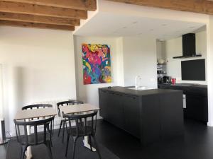 a kitchen with a table and chairs and a painting on the wall at appartement contemporain dans une authentique demeure viticole in Charnay-lès-Mâcon