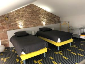 a room with two beds and a brick wall at appartement contemporain dans une authentique demeure viticole in Charnay-lès-Mâcon