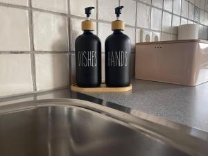 zwei schwarze Flaschen auf einer Theke neben einem Waschbecken in der Unterkunft TAMLiving Zentrum Luxus Parken Messe WIFI Traumaussicht Sunrise&Sunset in Graz