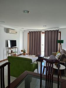 Búzios Lofts في بوزيوس: غرفة معيشة مع أريكة خضراء وطاولة