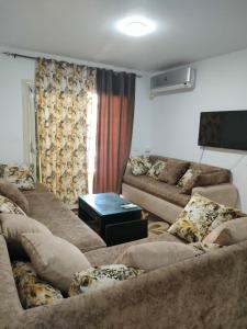 a living room with two couches and a table at دلتا مارينا in Al Ḩammād