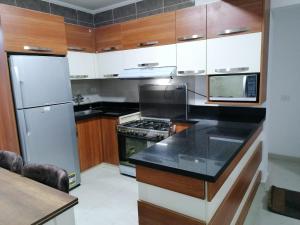 a kitchen with wooden cabinets and a black counter top at دلتا مارينا in Al Ḩammād