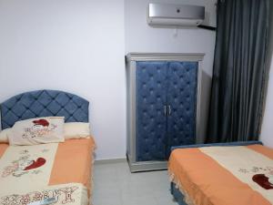 a bedroom with two beds and a blue cabinet at دلتا مارينا in Al Ḩammād