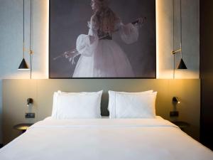 a bedroom with a large white bed with a painting above it at Radisson RED Berlin Kudamm in Berlin