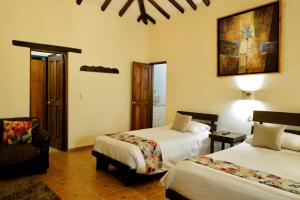 una habitación de hotel con 2 camas y una silla en Bombon Hotel, en Villa de Leyva