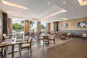 Radisson Hotel Muscat Panorama في مسقط: مطعم فيه طاولات وكراسي في الغرفة
