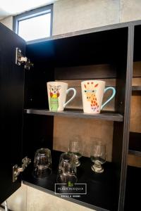 zwei Kaffeetassen und Gläser auf einem Regal in der Unterkunft A28 Full Suite ‖ Mini Dept at Plaza Acequia in Municipio Cuautitlán Izcalli