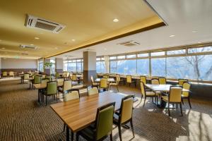 uma sala de jantar com mesas, cadeiras e janelas em 阿蘇CANYON TERRACE＆LODGE em Kurogawa