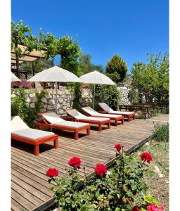 a bunch of chairs and umbrellas on a wooden deck at Tsira Taş Otel in Döşeme