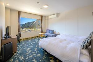 ein Hotelzimmer mit einem Bett und einem großen Fenster in der Unterkunft 阿蘇CANYON TERRACE＆LODGE in Kurokawa Onsen