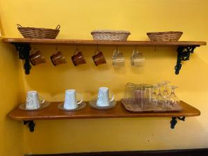 a shelf with mugs and cups on a wall at Chalé Laranja - Sítio Caldeirão in Posse +42 photos