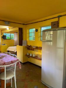 a kitchen with a refrigerator and a table and a bed at Chalé Laranja - Sítio Caldeirão in Posse +44 photos