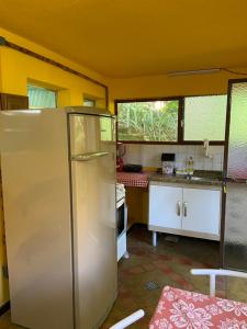 a kitchen with a refrigerator in the middle of a room at Chalé Laranja - Sítio Caldeirão in Posse