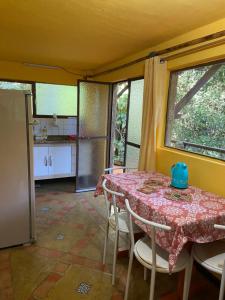 a dining room with a table and a kitchen at Chalé Laranja - Sítio Caldeirão in Posse