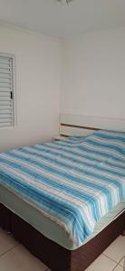 a bed with a blue and white striped blanket on it at Apartamento 3 quartos em Hortolândia in Hortolândia +31 photos