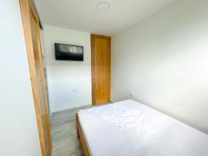 ein weißes Bett in einem Zimmer mit einem TV an der Wand in der Unterkunft Apartamento Villa Carolina 102 in Coveñas
