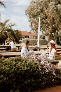 Kangaroo Island Seaview Motel في كنغزكوت: مجموعة من الناس يجلسون على مقاعد الحديقة