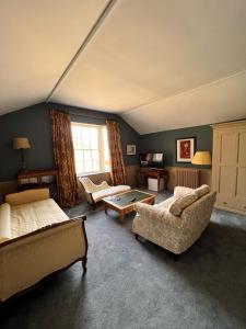 Habitación con 2 camas, sofá y mesa. en Llanerchydol Hall Suites, en Welshpool