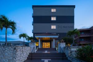 ein schwarzes Gebäude mit Palmen davor in der Unterkunft Nest Hotel Ishigaki Maesato Beach in Ishigaki-jima